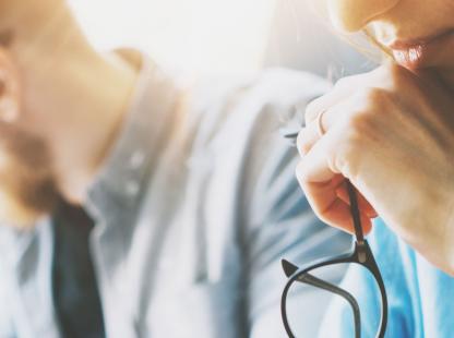 photo of a woman thinking with her glasses by her chin